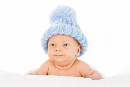 baby in blue knitted hat on top of a white blanket