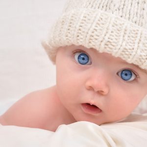 baby with blue eyes and a white knitted hat